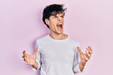 Yakışıklı hippi genç adam gündelik beyaz gömlek giyiyor deli gibi bağırıyor ve bağırıyor agresif bir ifade ve kollar havada. hüsran kavramı. 