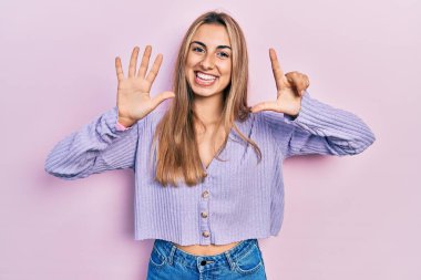 Gündelik tişört giyen güzel İspanyol kadın yedinci parmaklarını gösterip gösterirken kendine güvenen ve mutlu bir şekilde gülümsüyor.. 