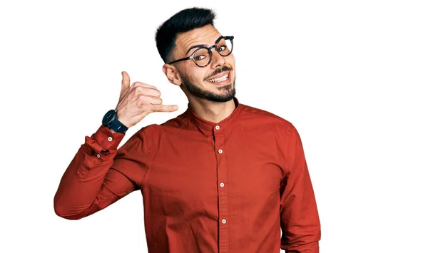 一个留着胡子 穿着商务衬衫 戴着眼镜的年轻人 手指手画脚地做着电话手势 就像在电话里说话一样 交流概念 — 图库照片