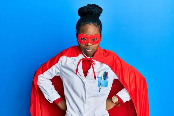 年轻的非洲裔美国女人穿着医生制服 穿着超级英雄服装 对自己的行为表示怀疑和紧张 因为问题而皱着眉头 消极的人 — 图库照片