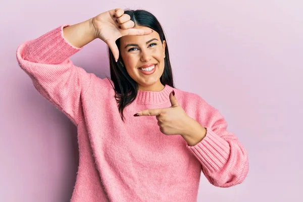 幸せな顔をした手と指でフレームを作る笑顔カジュアルな冬のセーターを身に着けている美しいブルネットの女性 創造性と写真の概念 — ストック写真
