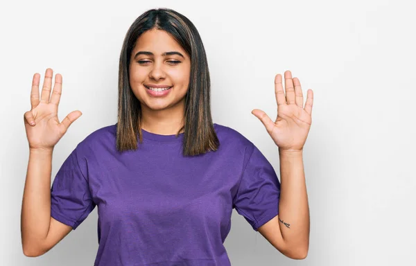 年轻的惊慌失措的女孩穿着休闲的紫色T恤 带着自信和快乐的笑容 指指点着9号手指 — 图库照片
