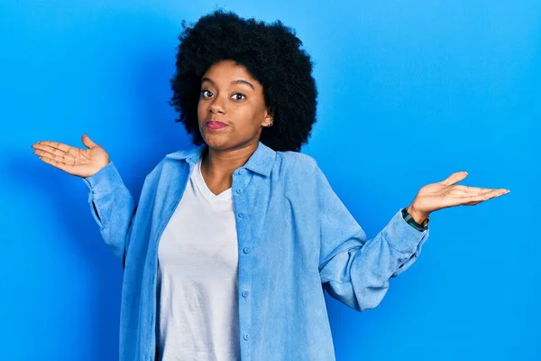 若いアフリカ系アメリカ人女性は カジュアルな服を着て腕や手を上げて混乱した表情をしています 疑わしい概念 — ストック写真