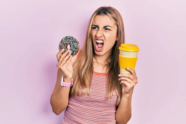 美しいヒスパニック系の女性ドーナツを食べ コーヒーを飲んで怒りと怒りを叫び 怒りで叫んで怒っている 怒りと攻撃的な考え方 — ストック写真