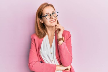 İş stili ve gözlüklü genç beyaz kadın kameraya kendinden emin bakıyor kollarını kavuşturmuş ve çenesini kaldırmış gülümsüyor. Olumlu düşünmek. 