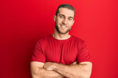 Gündelik kıyafetler giyen, kolları çapraz gülümseyen, kameraya bakan beyaz bir genç. pozitif kişi. 