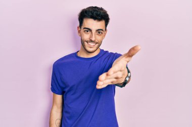 Gündelik tişört giyen, neşeli gülümseyen, yardım eli uzatan ve kabul gören genç İspanyol bir adam.. 