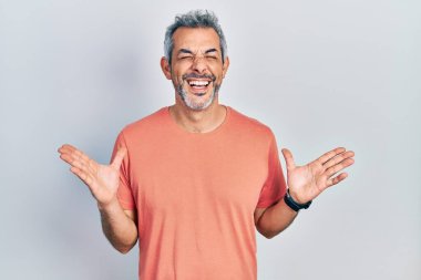 Gri tişörtlü, yakışıklı, orta yaşlı, başarıyı kutlamak için deli ve deli gömleği giyen, kollarını kaldırmış, gözleri kapalı, heyecanlı bir şekilde bağıran bir adam. Kazanan konsept 