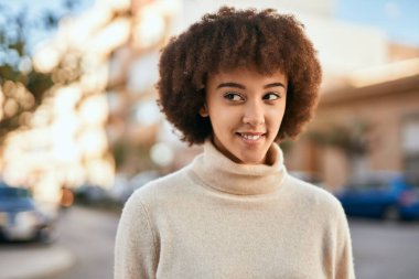 Genç İspanyol kız gülümseyerek şehirde mutlu mesut dikiliyor..