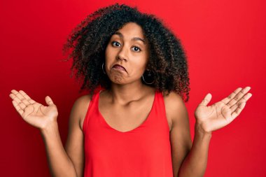 Afro saçlı güzel Afro-Amerikalı kadın. Sıradan kıyafetler giyiyor. Hiçbir şeyden habersiz ve kolları açık, hiçbir fikri yok.. 