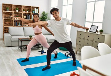 Genç Latin sporcu çift gülümseyerek evde mutlu bir antrenman yapıyor..