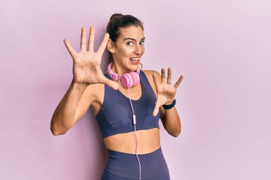 Spor kıyafetleri giyen ve kulaklık takan genç ve güzel bir kadın korku ifadesinden korkmuş ve dehşete düşmüş. El hareketlerini durdur, şok içinde bağır. panik konsepti. 