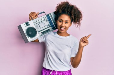 Güzel Afrikalı Amerikalı kadın, afro saçlı, antreman kıyafetleri giyen ve elinde teyp ile mutlu bir şekilde gülümseyen. 