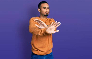 Genç Afro-Amerikalı, günlük giysiler giymiş, reddedilmiş, kollarını kavuşturmuş, olumsuz işaretler veren, kızgın yüzlü. 