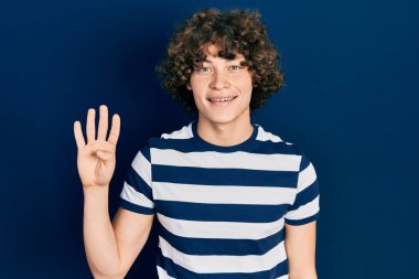 Yakışıklı, çizgili tişört giyen, dört numarayı gösteren ve gülümseyen, kendinden emin ve mutlu bir genç.. 