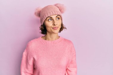 Şirin yün şapkalı genç esmer kadın yan tarafa bakıyor ve düşünüyor.. 