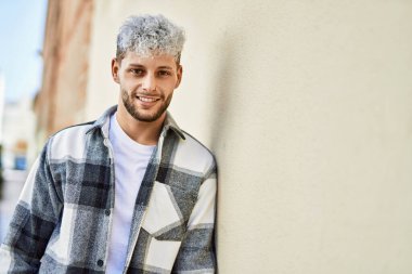 Genç İspanyol adam gülümseyerek şehirde mutlu mesut dikiliyor..