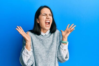 Gündelik kıyafetler giyen genç İspanyol kadın başarı için deli ve çılgınlığı kutluyor kollarını kaldırmış ve gözlerini kapatmış heyecanla bağırıyor. Kazanan konsept 