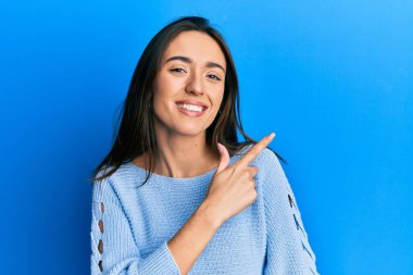 Yüzünde mutlu ve doğal bir ifade olan, elleri ve parmaklarıyla işaret eden, güler yüzlü, gündelik kıyafetler giyen genç İspanyol kız. 