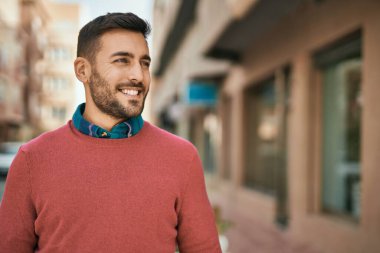 Genç İspanyol adam gülümseyerek şehirde mutlu mesut dikiliyor..