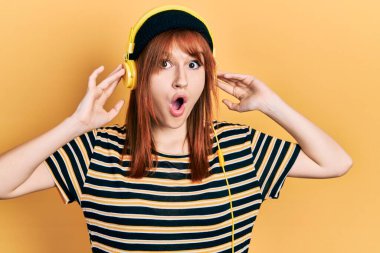 Kızıl saçlı, müzik dinleyen genç bir kadın. Kulaklık takıyor. Şok olmuş ve korkmuş.. 