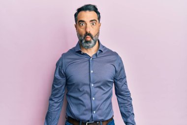 Sakallı ve gri saçlı orta yaşlı bir adam iş kıyafetleri giymiş dudaklarıyla balık suratı yapan, çılgın ve komik bir jest yapan. Komik ifade. 