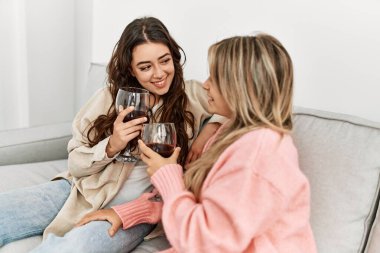 Genç çift mutlu bir şekilde kadeh kaldırıyor kırmızı şarap kadehiyle evde..