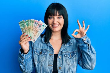 Birleşik Arap Emirlikleri 'ni elinde tutan genç İspanyol kadın Dirham banknotları parmaklarıyla imza atıyor, gülümseyerek mükemmel bir sembol oluşturuyor. 