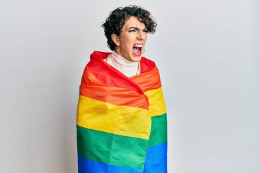 Gökkuşağı lgbtq bayrağına sarılı makyaj yapan genç bir adam kızgın ve öfkeli bağırıyor ve öfkeyle bağırıyor. öfke ve agresif konsept. 