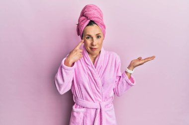 Duş havlusu şapkası ve bornoz giyen genç sarışın kadın avuç içinin açık olup fotokopi alanını ve alnını göstermekten rahatsız oluyor. Bunu bir düşün.. 