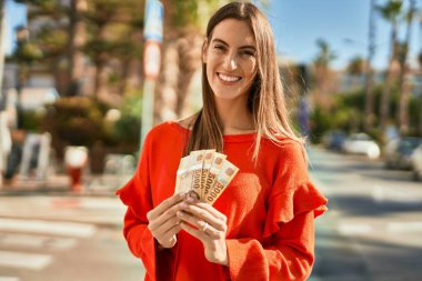 Genç İspanyol kadın gülümsüyor. Mutlu bir şekilde şehirde Macar banknotları tutuyor..