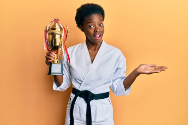 Genç Afrikalı Amerikalı kız karate kimonosu giyip zaferi mutlu bir gülümsemeyle ve kazanan ifadeyle kutluyor. 