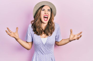 Genç İspanyol kız yaz şapkası takmış deli deli deli bağırıyor ve bağırıyor agresif bir ifade ve kollar havada. hüsran kavramı. 