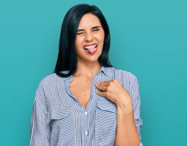 Günlük kıyafetler giyen beyaz bir kadın komik bir ifadeyle dilini dışarı çıkarıyor. duygu kavramı. 