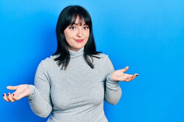 Gündelik kıyafetler giyen, elleri ve kolları havada, kafası karışmış genç İspanyol kadın. şüphe kavramı. 