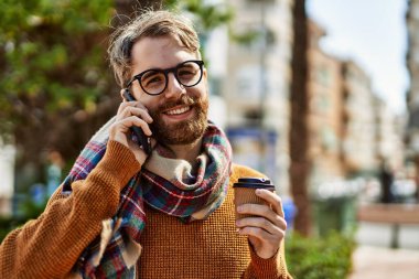 Beyaz sakallı bir adam güneşli bir günde telefonda konuşuyor.