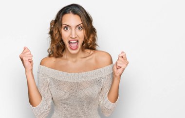 Gündelik giysiler giyen genç, güzel beyaz bir kadın kollarını kaldırıp, gözleri açık bir şekilde başarıyı kutluyor. Kazanan konsept. 