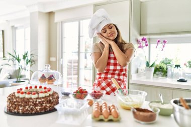 Güzel, genç, esmer pasta şefi kadın mutfakta hamur işleri pişiriyor. Yorgun uyuyor, hayal kuruyor, elleriyle poz veriyor ve gözleri kapalı gülümsüyor.. 