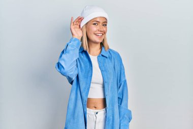 Yün şapka takan güzel sarışın kadın kulağına fısıldayarak dedikoduları ve dedikoduları dinliyor. Sağırlık kavramı. 