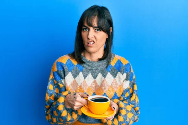 Genç İspanyol kadın bir fincan kahve içiyor habersiz ve kafası karışmış bir ifade. şüphe kavramı. 