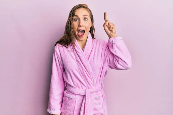 若いブロンドの女性が成功したアイデアで指を指してバスローブを着ています 興奮して幸せよ 第1位 — ストック写真