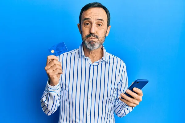 Μεσήλικας Ισπανόφωνος Χρησιμοποιώντας Smartphone Και Κρατώντας Πιστωτική Κάρτα Φουσκώνει Μάγουλα — Φωτογραφία Αρχείου