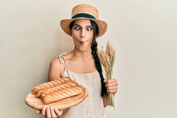 若いですヒスパニック系の女性を保持自家製パンとスパイク小麦作る魚の顔と口と目を細めて クレイジーでコミカルな — ストック写真