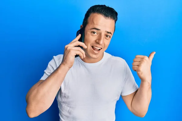 Handsome Young Man Having Conversation Talking Smartphone Pointing Thumb Side — Stock Photo, Image