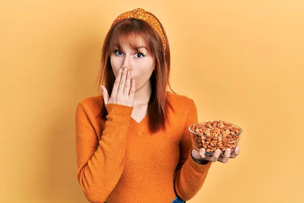 Redhead Young Woman Holding Peanuts Covering Mouth Hand Shocked Afraid — Stock Photo, Image