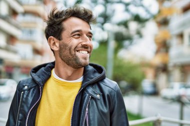 Yakışıklı, sakallı, açık havada mutlu gülümseyen bir İspanyol.