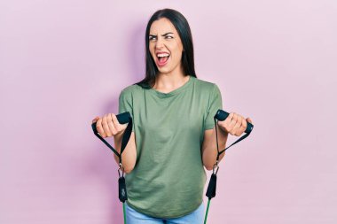 Mavi gözlü güzel bir kadın kol direnci eğitiyor. Kol bantları kızgın ve kızgın çığlık atıyor. Öfkeli ve öfkeyle bağırıyor. öfke ve agresif konsept. 