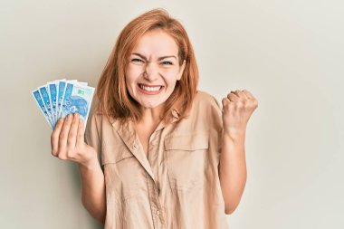 Kafkasyalı genç bir kadın 50 Polonya parası tutuyor. Gururla bağırıyor, zaferi kutluyor ve başarıyı kollarını kaldırarak kutluyor. 