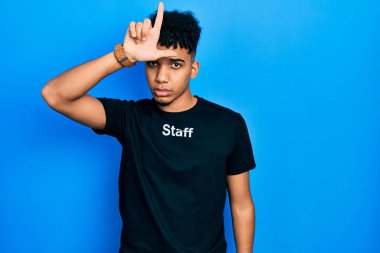 Genç Afrikalı Amerikalı adam, personel tişörtü giyiyor. Alnında parmakları olan insanlarla dalga geçiyor. Ezik hareketler yapıyor, alay ediyor, hakaret ediyor.. 
