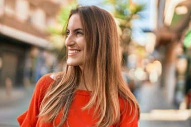 Genç İspanyol kadın gülümseyerek şehirde mutlu mesut dikiliyor..